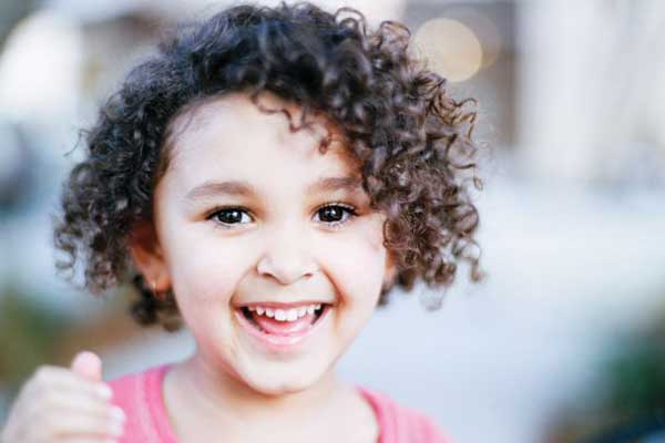 Smiling child with curly hair outdoors