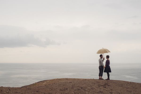 Couple standing under umbrella by the sea