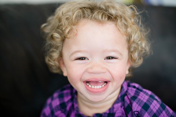 Smiling toddler with curly hair in purple shirt