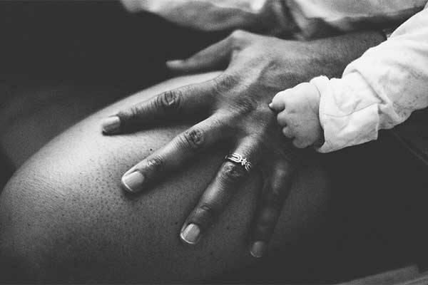 Baby hand holding adult hand in black and white