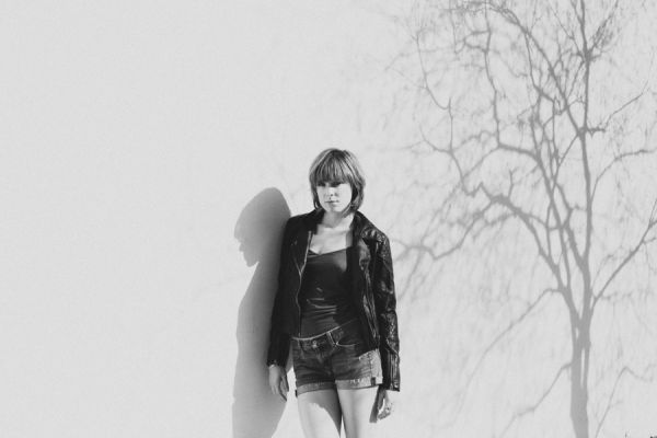 Person standing by wall with tree shadow