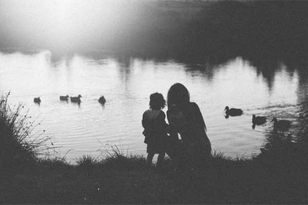 Silhouettes by a lake with ducks at sunset