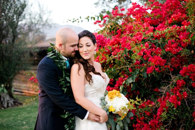 Bride and groom embracing near vibrant red flowers