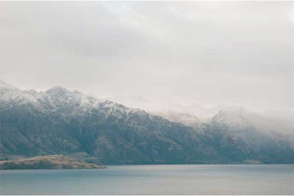 Snowy mountains above calm blue lake