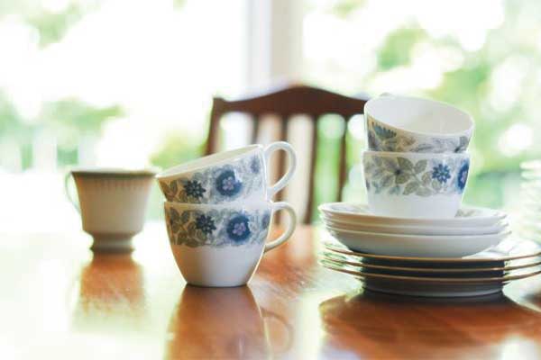 Stacked floral teacups and plates on wooden table