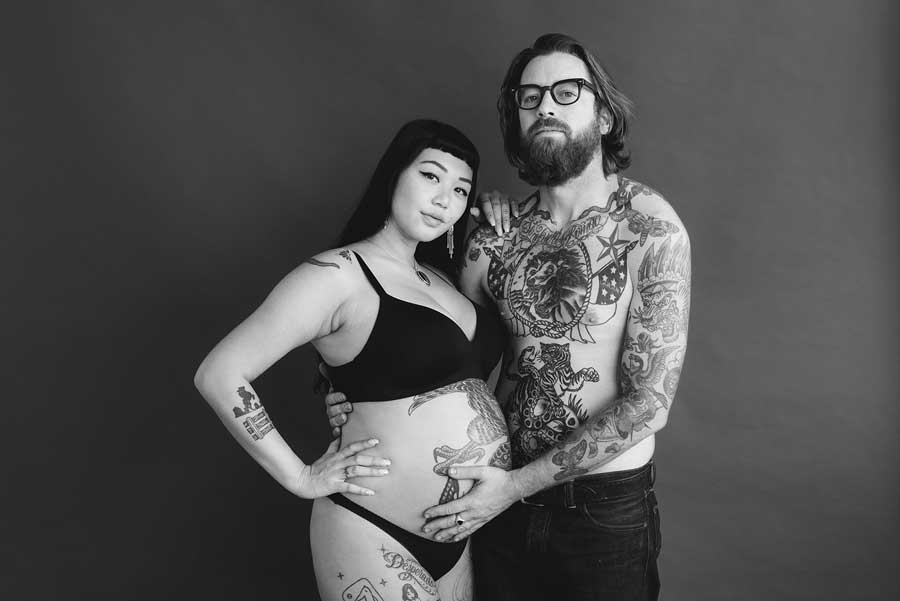 Tattooed couple embracing during pregnancy photoshoot