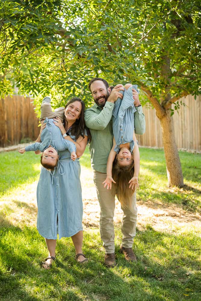 Parents holding children upside down in backyard