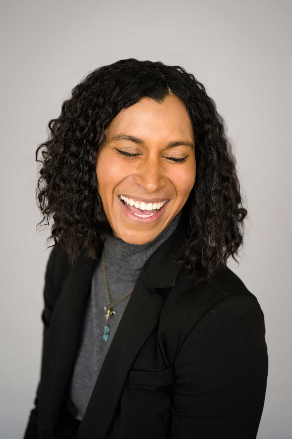 Headshots-Pricing-image Smiling woman with curly hair in black blazer