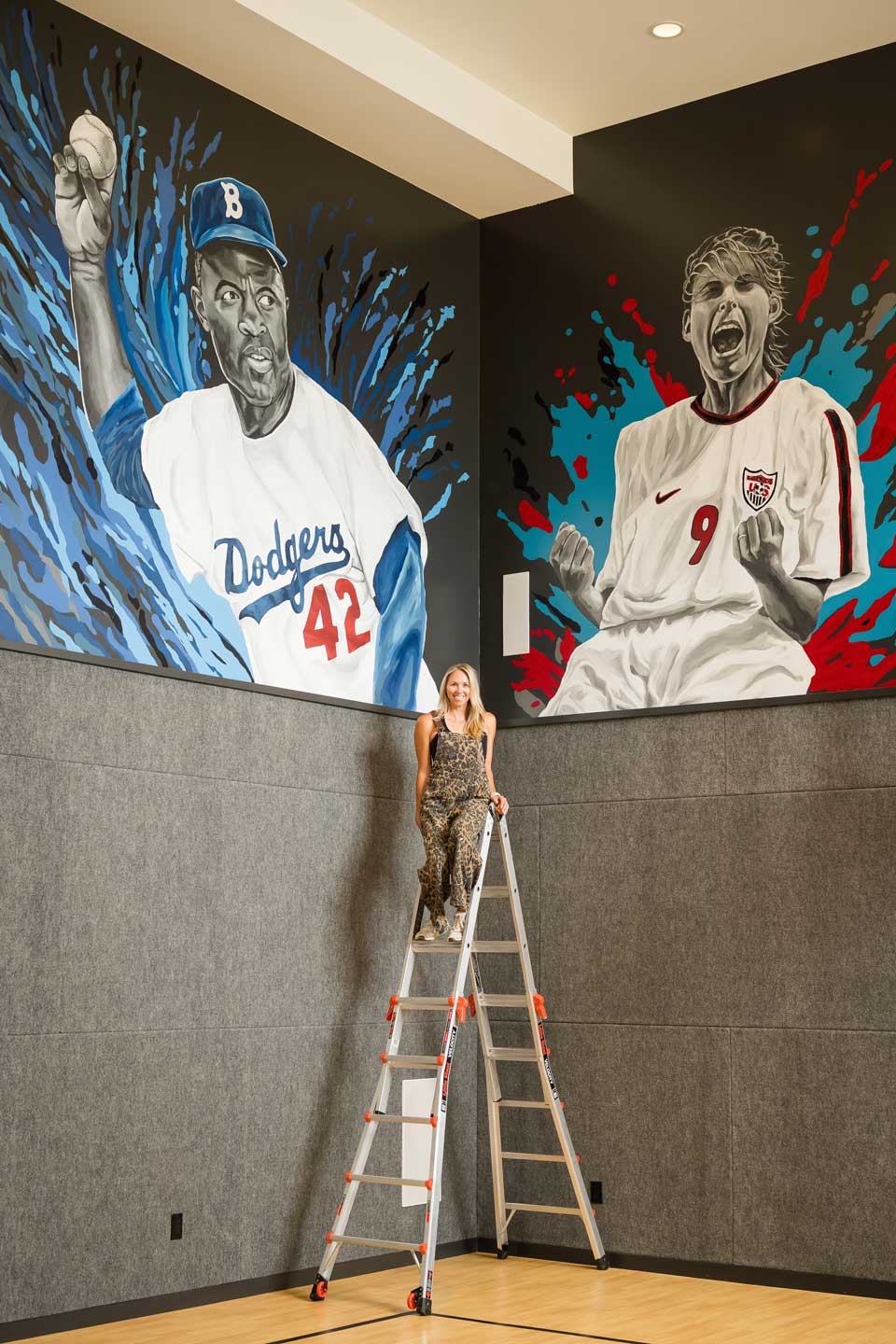 Woman on ladder between sports murals