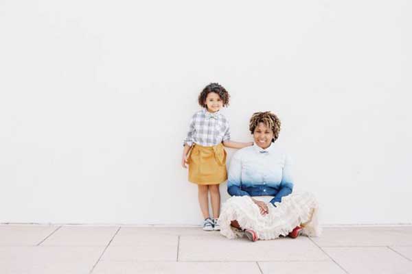 Smiling woman and child posing against white wall