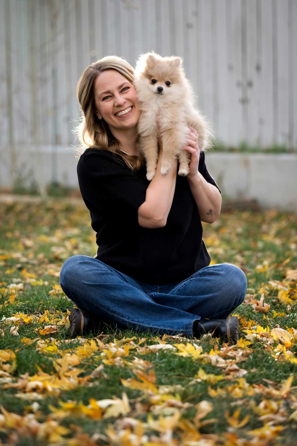 Woman holding fluffy Pomeranian puppy outdoors in autumn