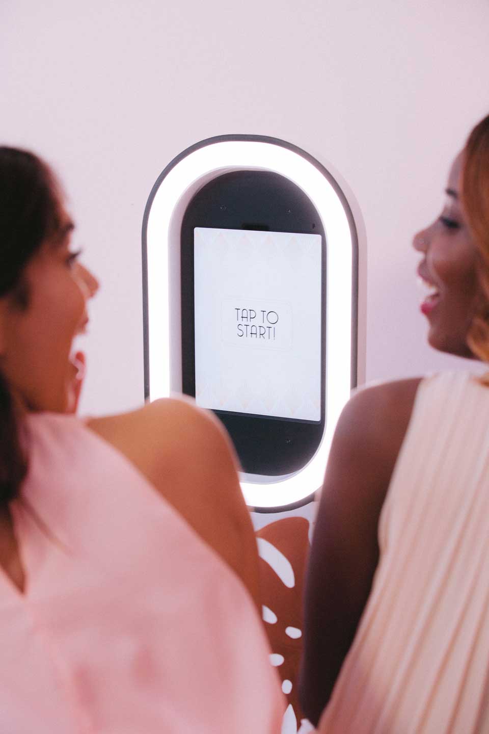 Two women using illuminated photo booth mirror
