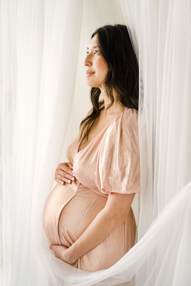Pregnant woman in pink dress holding belly - Pricing - Denver Maternity and Newborn Photographer
