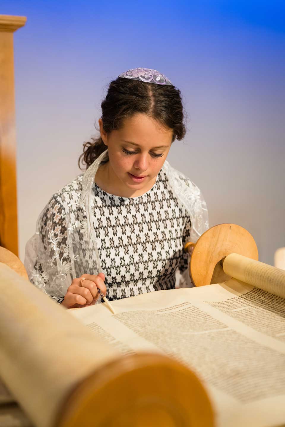Girl reading from Torah scroll in synagogue