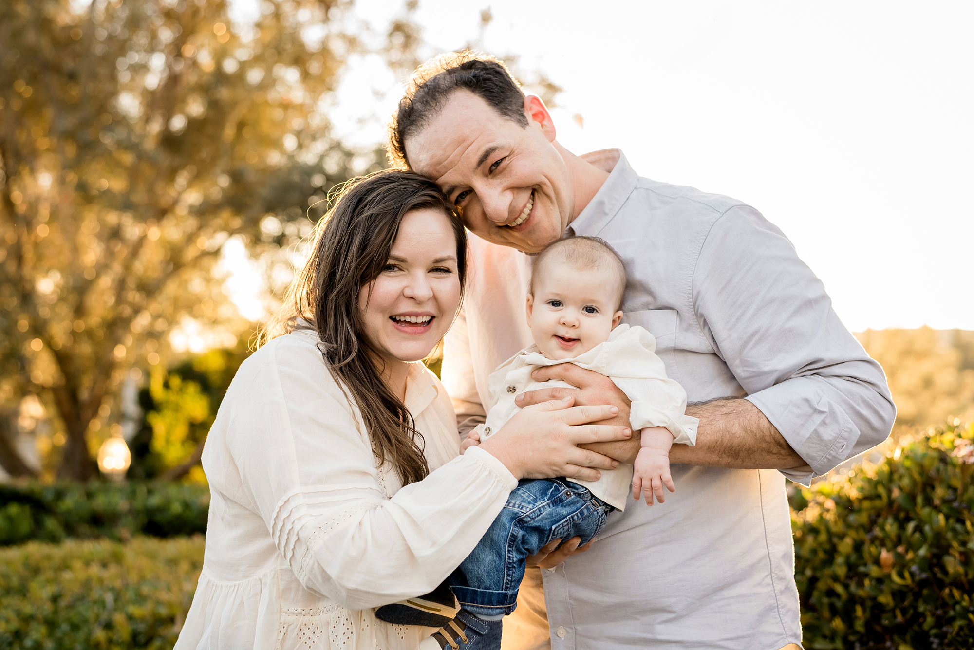 Smiling family holding baby outdoors