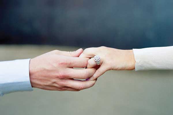 Couple holding hands with engagement ring