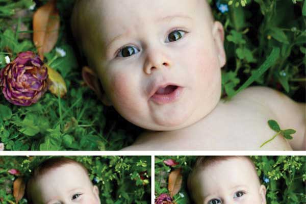 Smiling baby lying on green grass with flowers